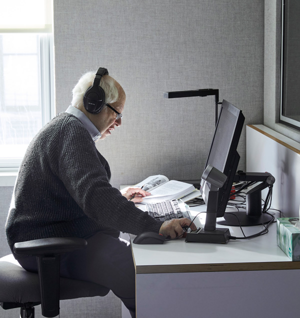 Image: The Gitlins, a pair of JBI volunteers, sitting in the recording booth preparing to read a book